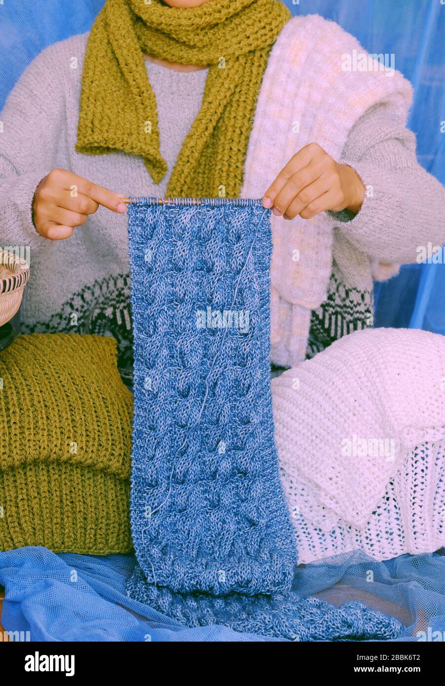 Concept woman wear blue jeans, white woolen sweater, sock, moss green wool scarf on blue background, hand knit handmade present make warm for winter Stock Photo