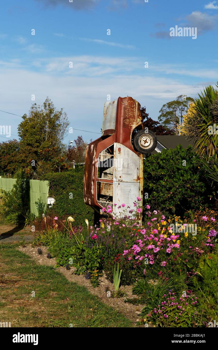 Car wreck half-buried in a front garden amongst the flowers. Better than a keep out sign. Stock Photo