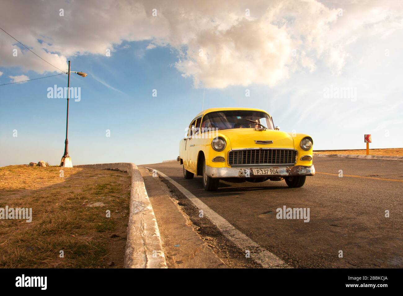 HAVANA, CUBA - MARCH 31, 2017: Old and rusty yellow American car driving on a Havana highway. Cuba Stock Photo