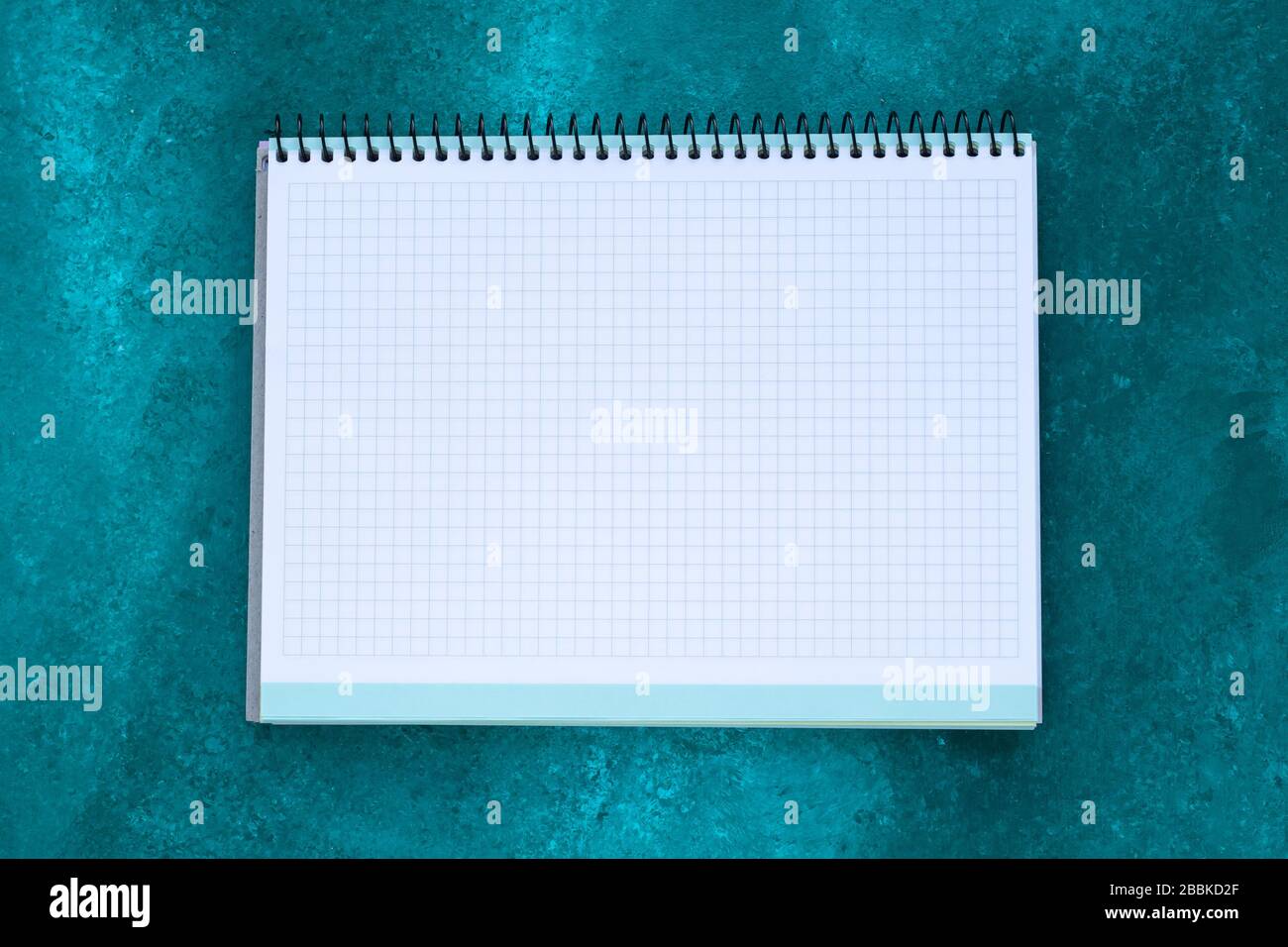 Empty squared notebook with copy space for text on abstract green painted background. Planning concept. White paper sheet, mock-up Stock Photo