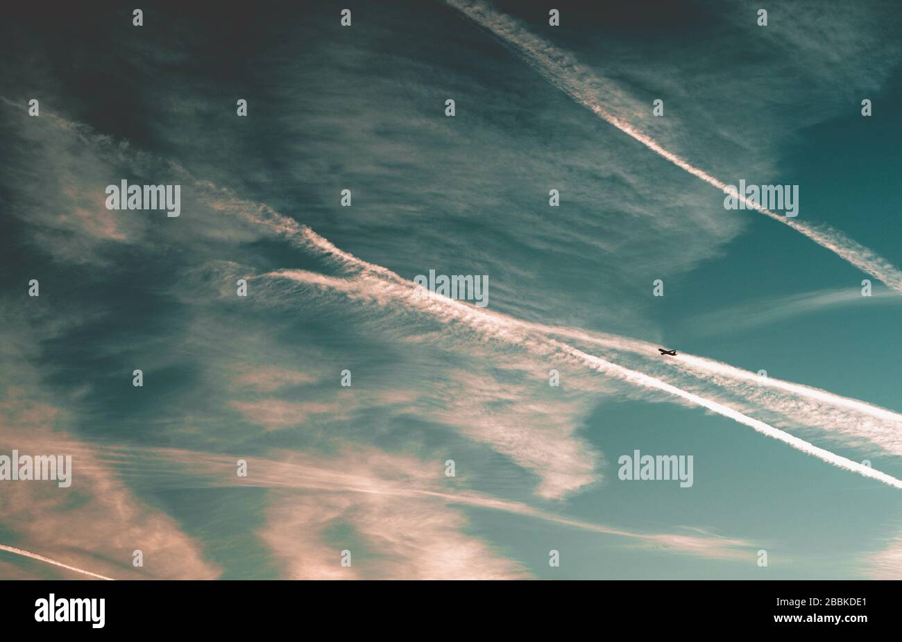 Skyline at sunset with airplane and condence trails Stock Photo