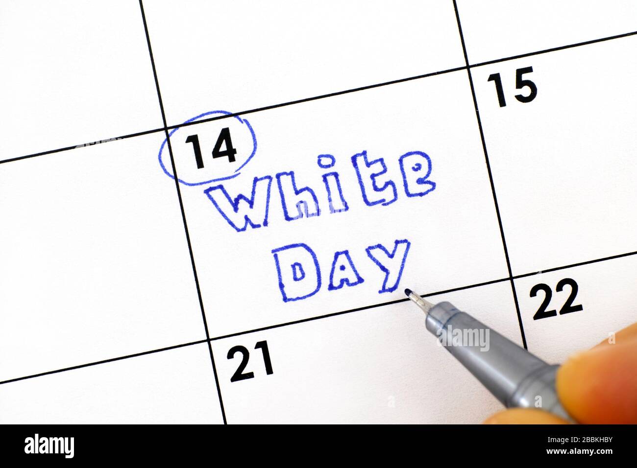 Woman fingers with pen writing reminder White Day in calendar.  March 14. Stock Photo