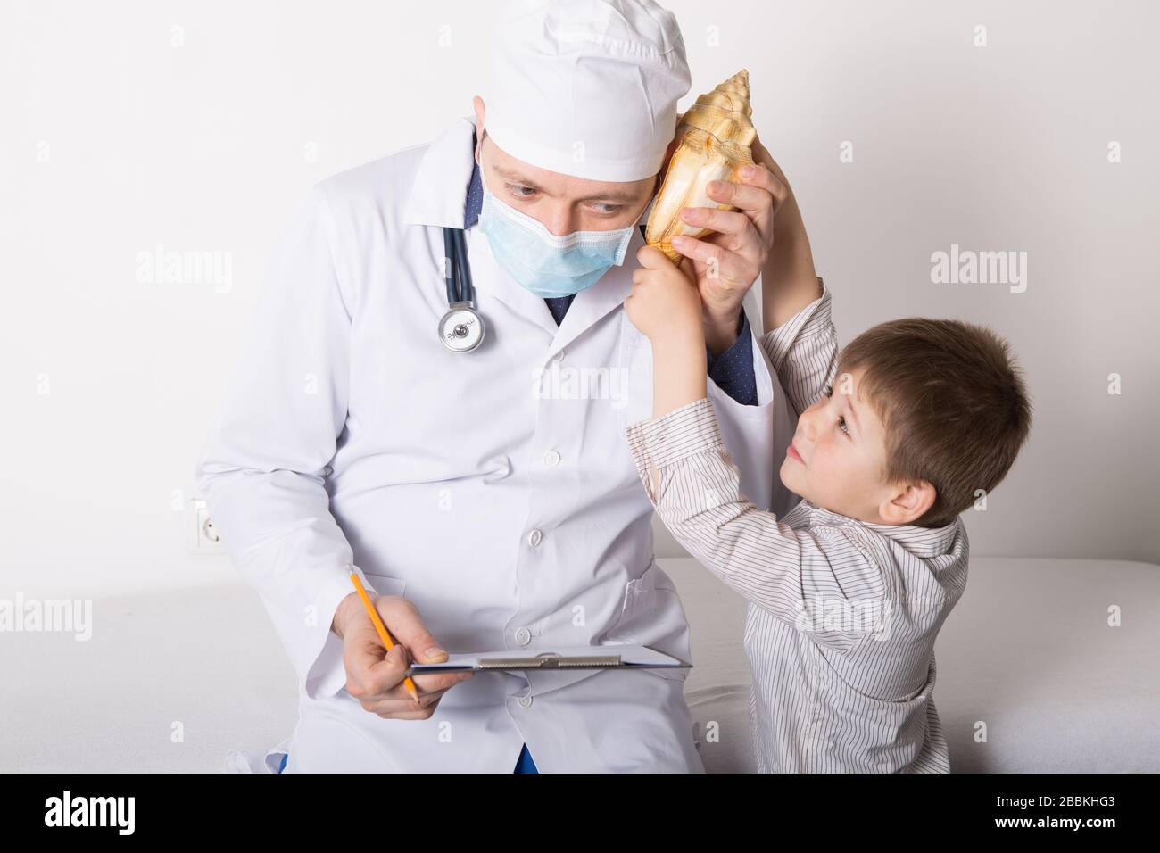 Boy gives a big shell to doctor. Portrait of smart pediatrician with little  patient in clinic office. Joyful kid smiling and performing approving ges  Stock Photo - Alamy