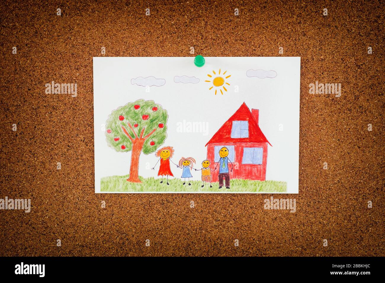 Drawing of a happy family and an apple tree and a house pinned on to cork board. Close up. Stock Photo