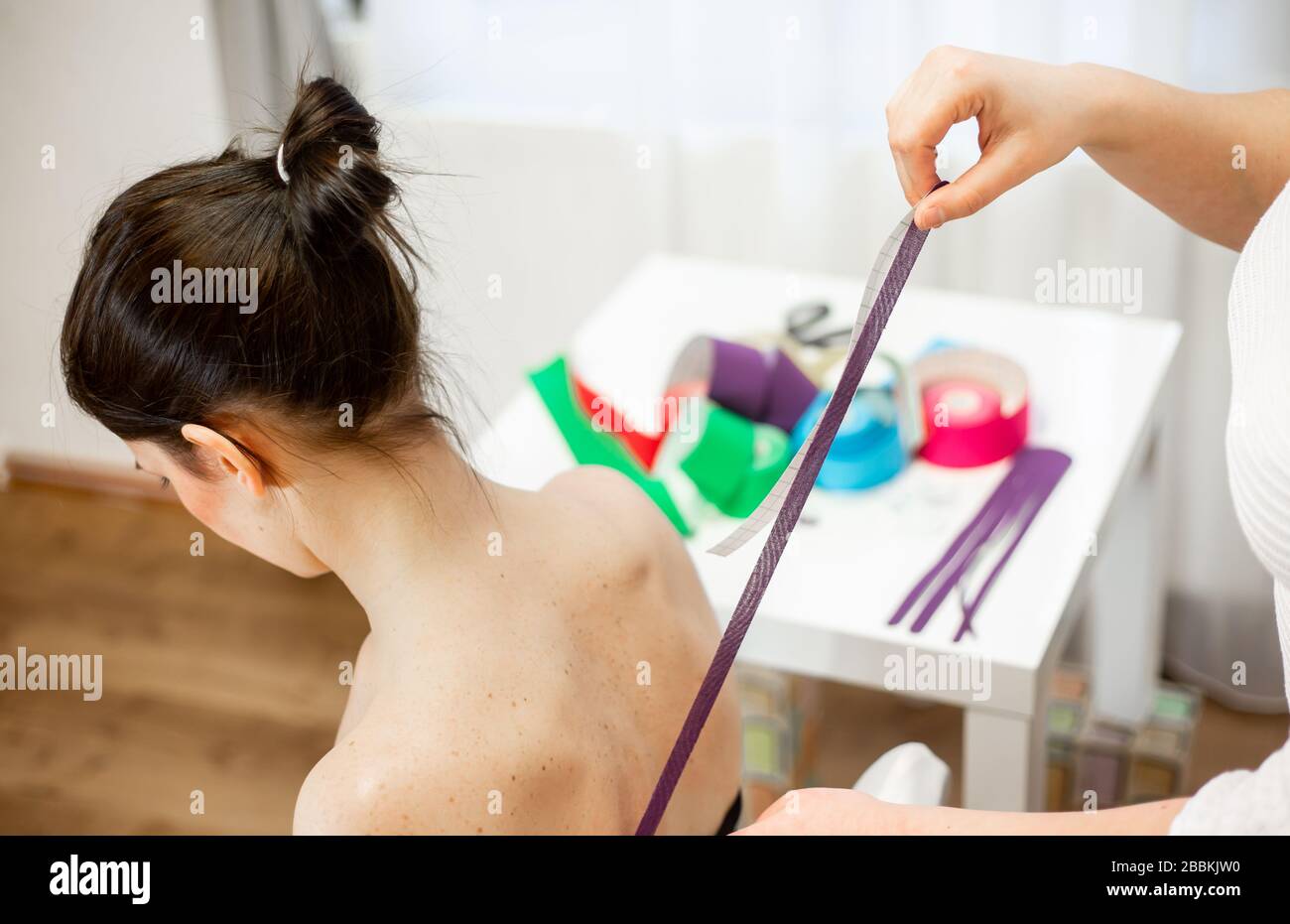 Professional physical therapist applying tape on patients shoulder, kinesiotaping concept Stock Photo