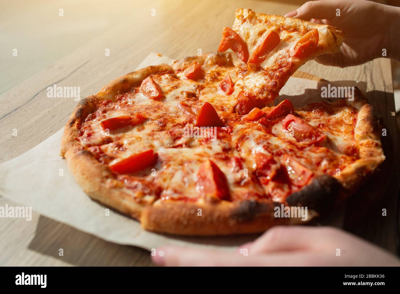 Big pizza stands on a table in a cafe close-up. Italian pizza cut on pieces. Stock Photo