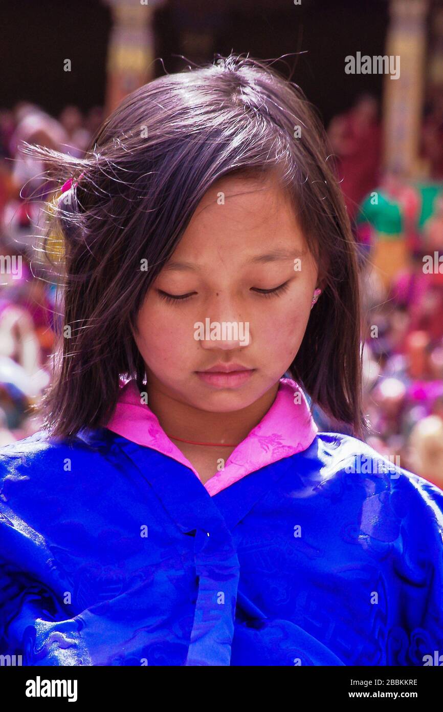 Portrait of a shy young girl wearing traditional costume of Kira (dress), and blue outer jacket (Tego)  at the Thimphu Tshechu Festival, Bhutan Stock Photo