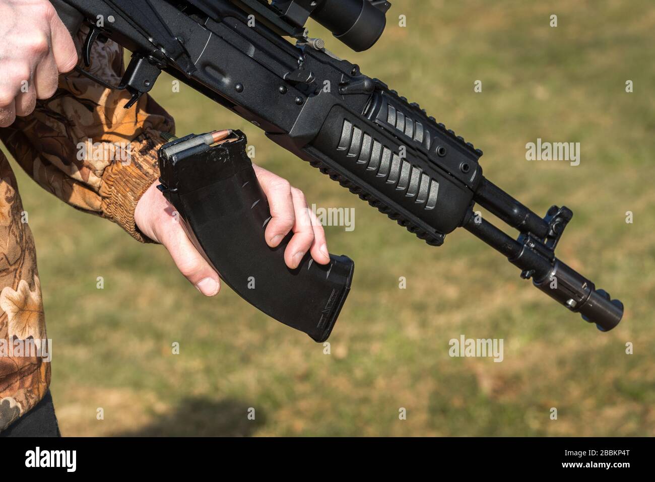 A man is holding a rifle magazine camouflage clothes Stock Photo