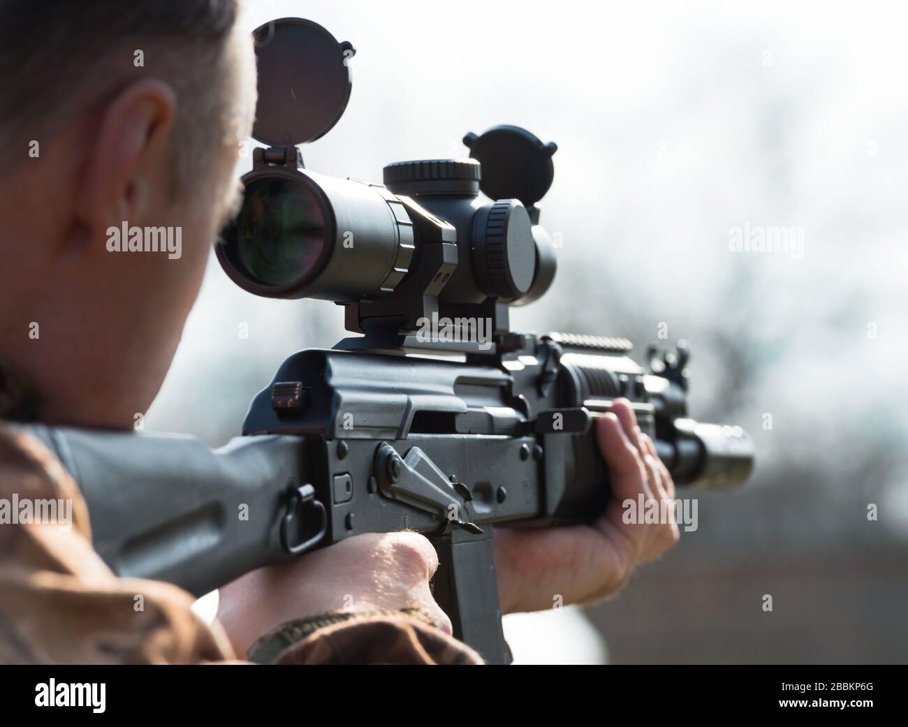 A man takes aim and shoots from Kalashnikov. Over the sholder. Stock Photo