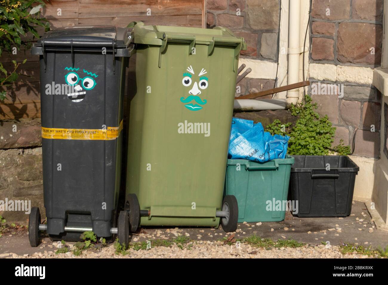 Bristol-March 2020- England-a close up view of a black and green wheeling rubbish bins with a funny face sticker on the side Stock Photo