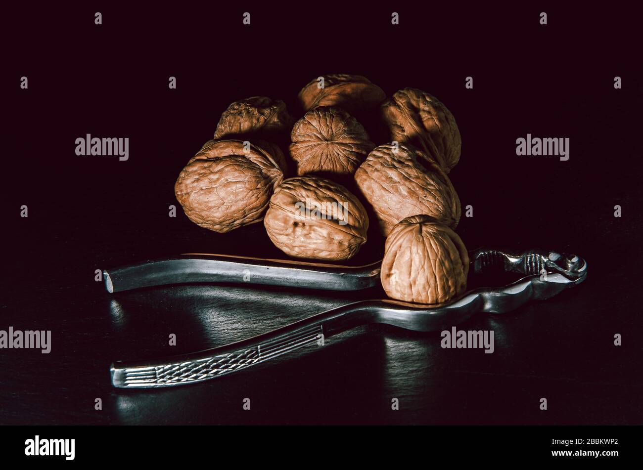 Walnuts with nutcracker over black background. Stock Photo