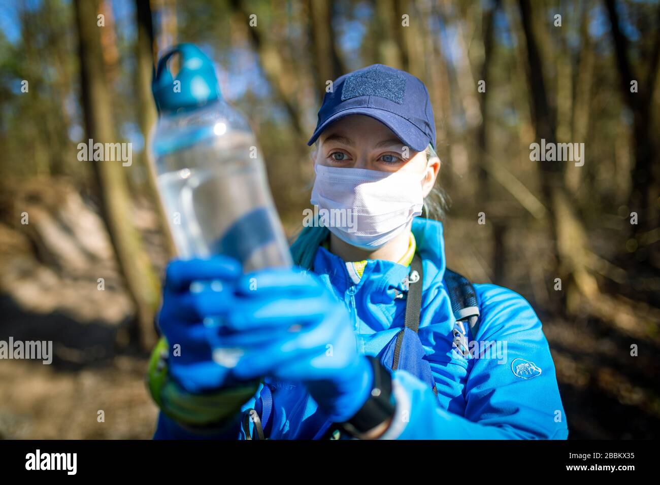 Ecologist taking water samples from a natural source in protective gloves and mask Stock Photo