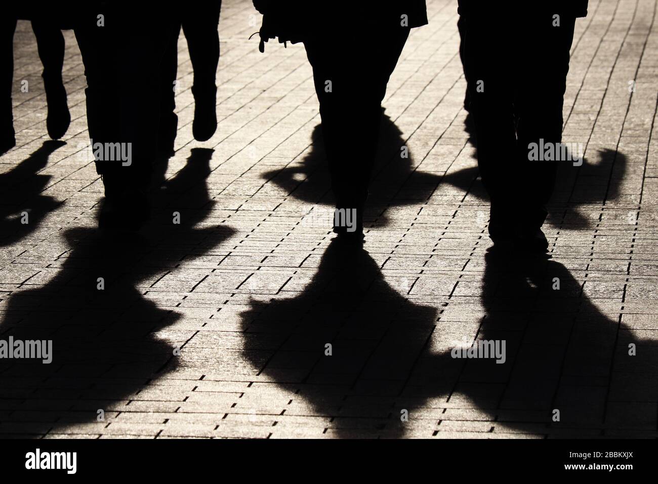 Silhouettes and shadows of people on the street. Crowd walking down on sidewalk, spread of infection during COVID-19 coronavirus pandemic, concept of Stock Photo