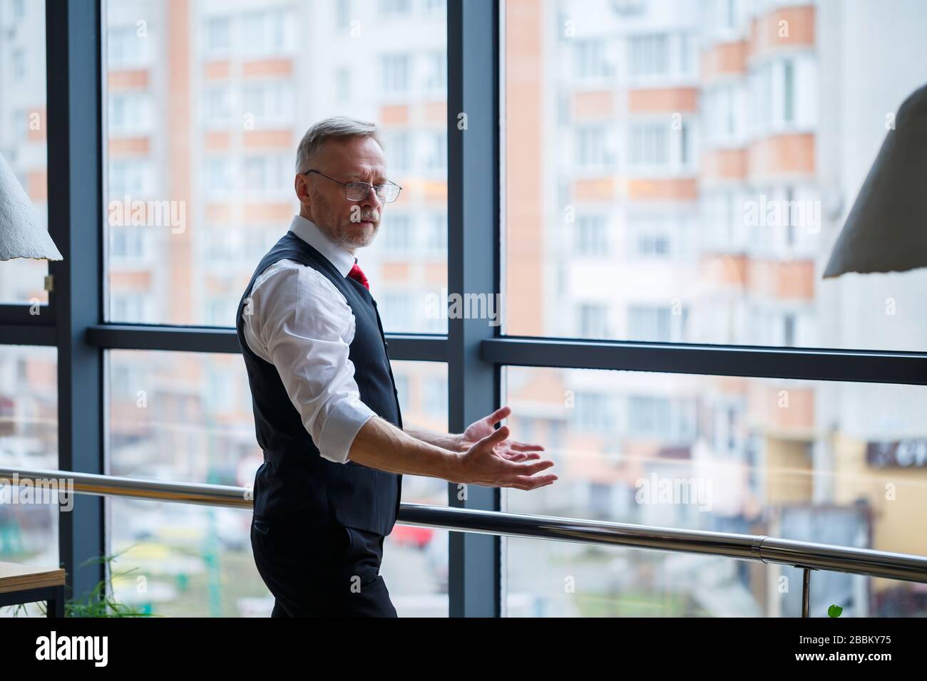 Smiling happy managing director thinks about his successful career development while stands in his office near the background of a window with copy sp Stock Photo