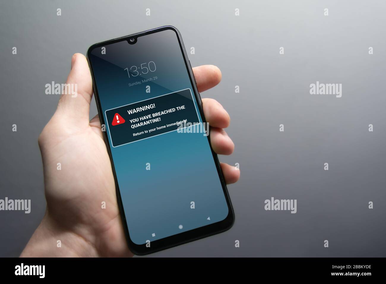 Quarantine breach alert mockup on smartphone being held in hand. Advice to stay in home quarantine to stop contagion. Pandemic, healthcare, technology Stock Photo