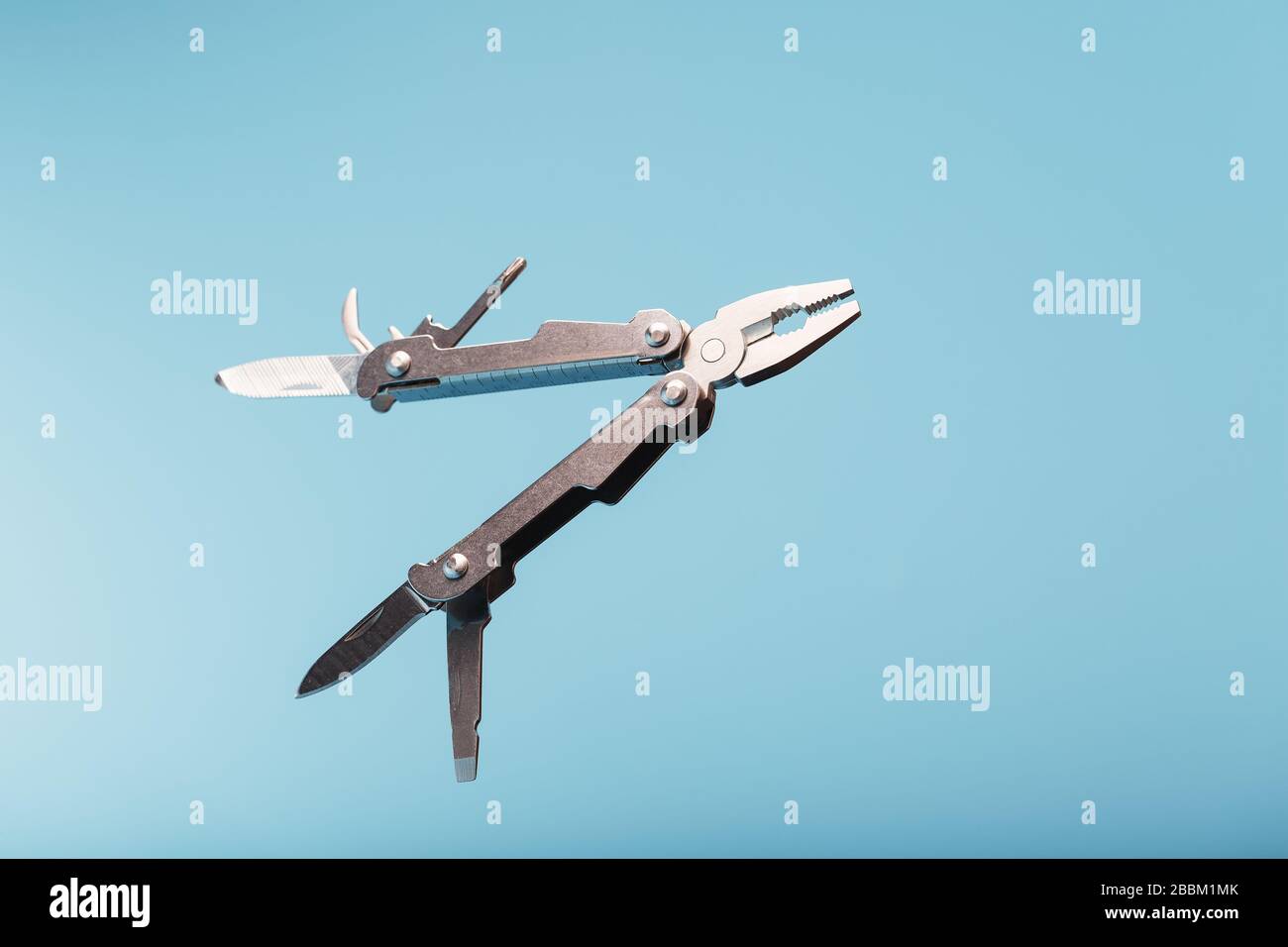 The multitool multi-function tool hovers on a blue background. The concept of an expanded multi-tool with free space. Stock Photo