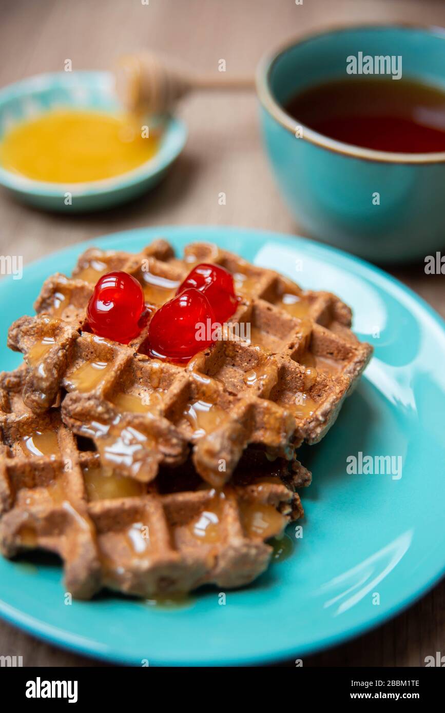 Vegan healthy waffles made in waffle maker with tea, honey and cinnamon
