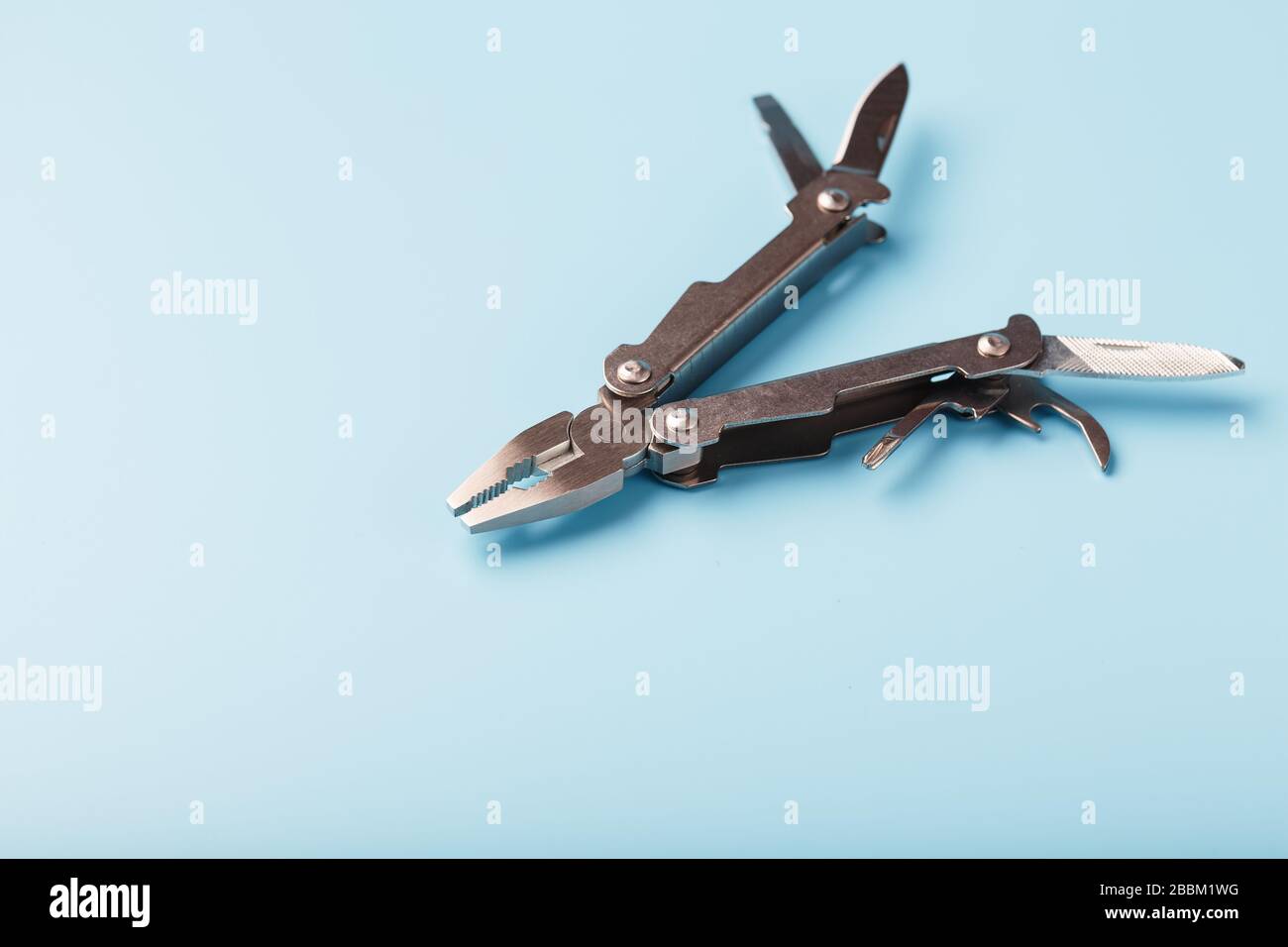 The multitool multi-function tool hovers on a blue background. The concept of an expanded multi-tool with free space. Stock Photo