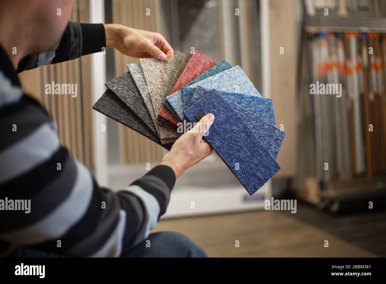 Man choosing the rigt colour of carpet for his new apartment in floor studio, flooring Stock Photo