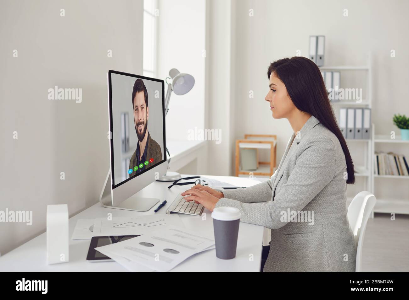 Work online. A business woman is sitting working at a computer at home indoors. Stock Photo