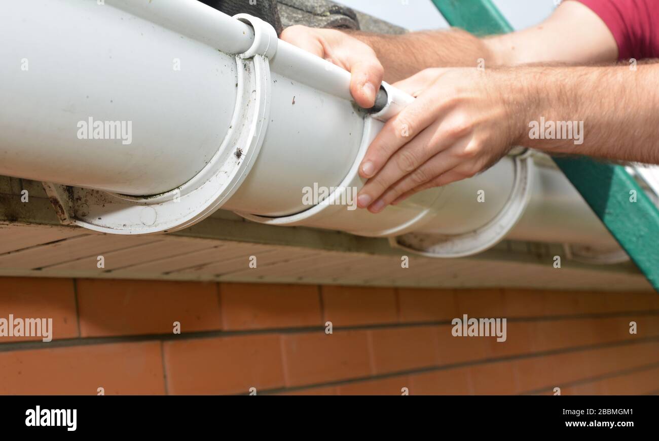 Guttering, Gutters, Plastic Guttering, Guttering & Drainage. Roofer contractor hands installing