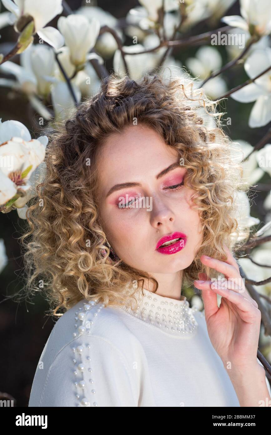 Portrait of beautiful girl with curly long hair in white blouse walks ...