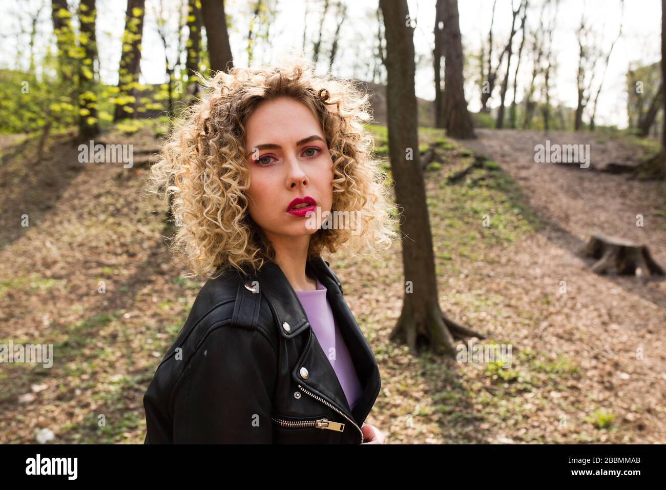 Portrait of a beautiful girl with curly long hair in black leather ...