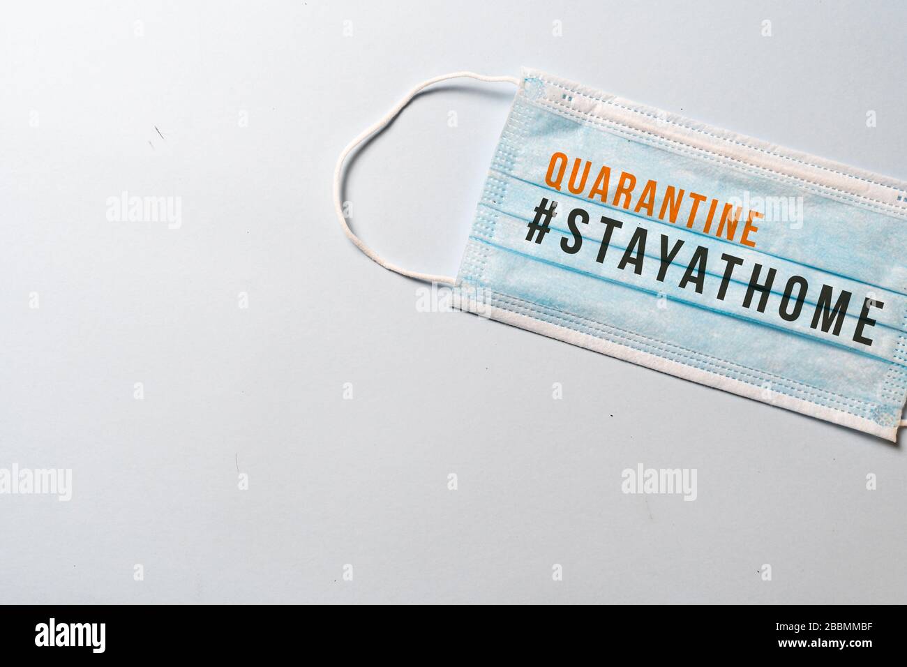 #STAYATHOME. surgical mask with showing the message "STAY AT HOME-QUATANTINE"., COVID-19,Virus prevention and quarantine minimal concept. White backgr Stock Photo