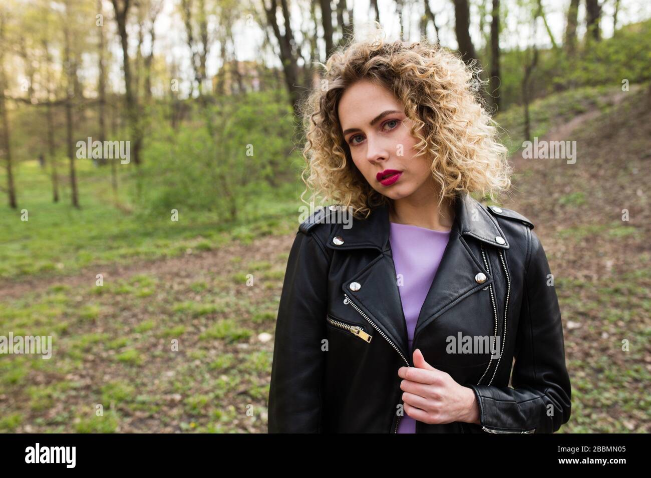 Portrait of a beautiful girl with curly long hair in black leather ...