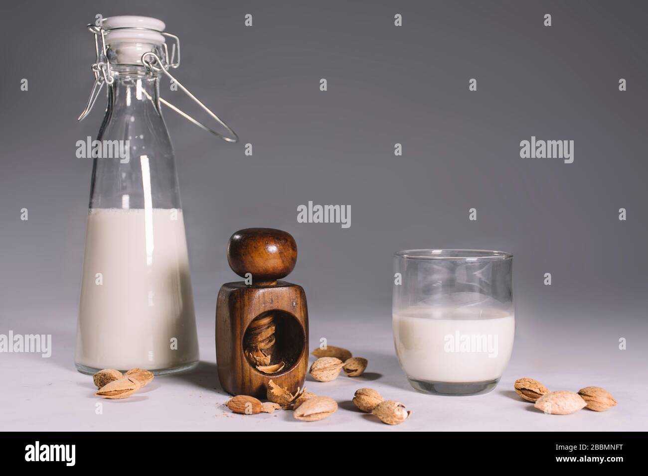 A nutcracker with open and closed almonds and a bottle and a glass with