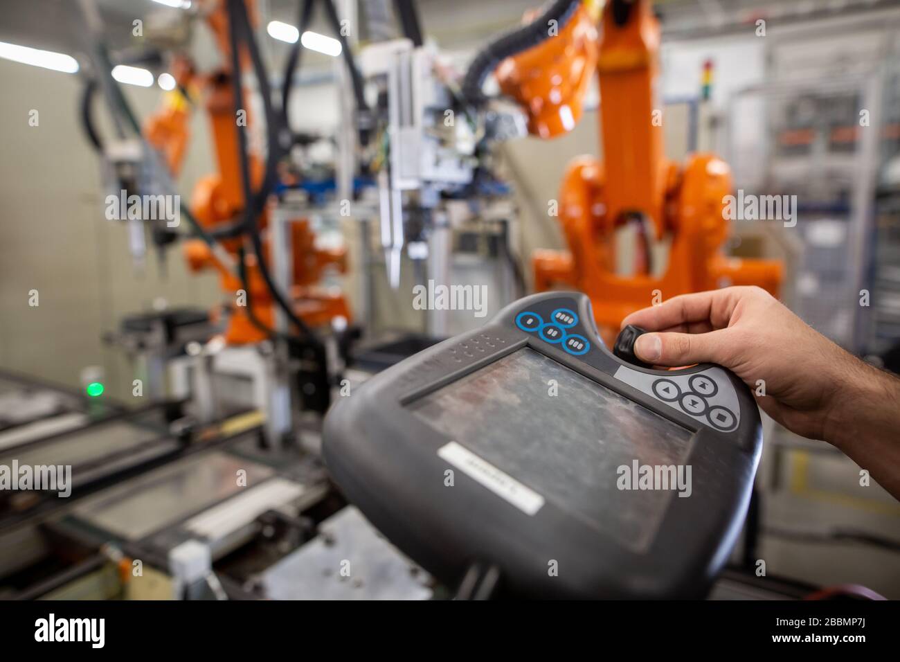 Young man programming industrial automatic robot in automotive industry Stock Photo