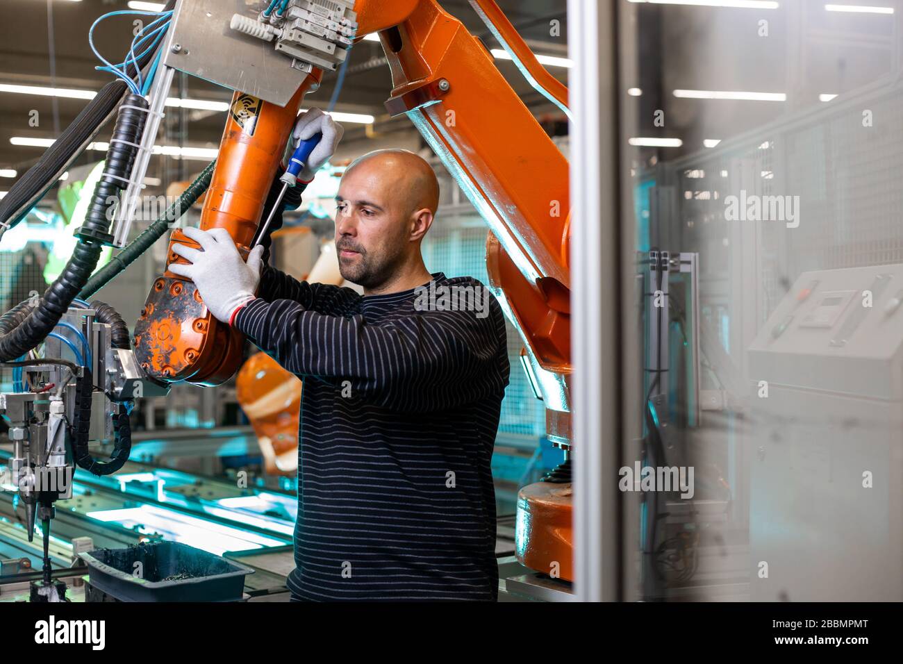 Factory engineer operating with automatic robot arms in automotive industry, modern automotive factory Stock Photo