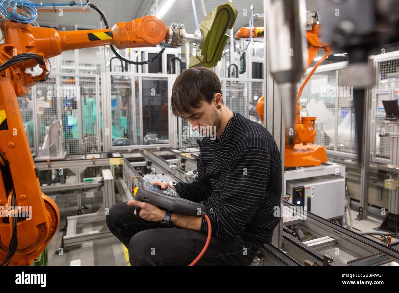 Young man programming industrial automatic robot in automotive industry Stock Photo