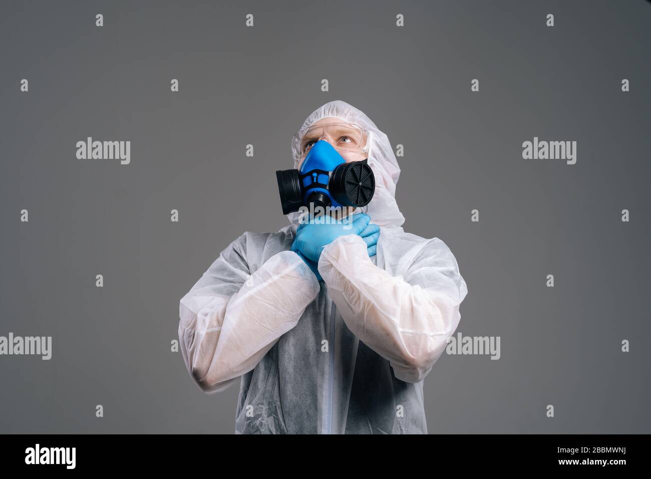 Medical worker in hazmat, goggles and respirator choking himself with ...