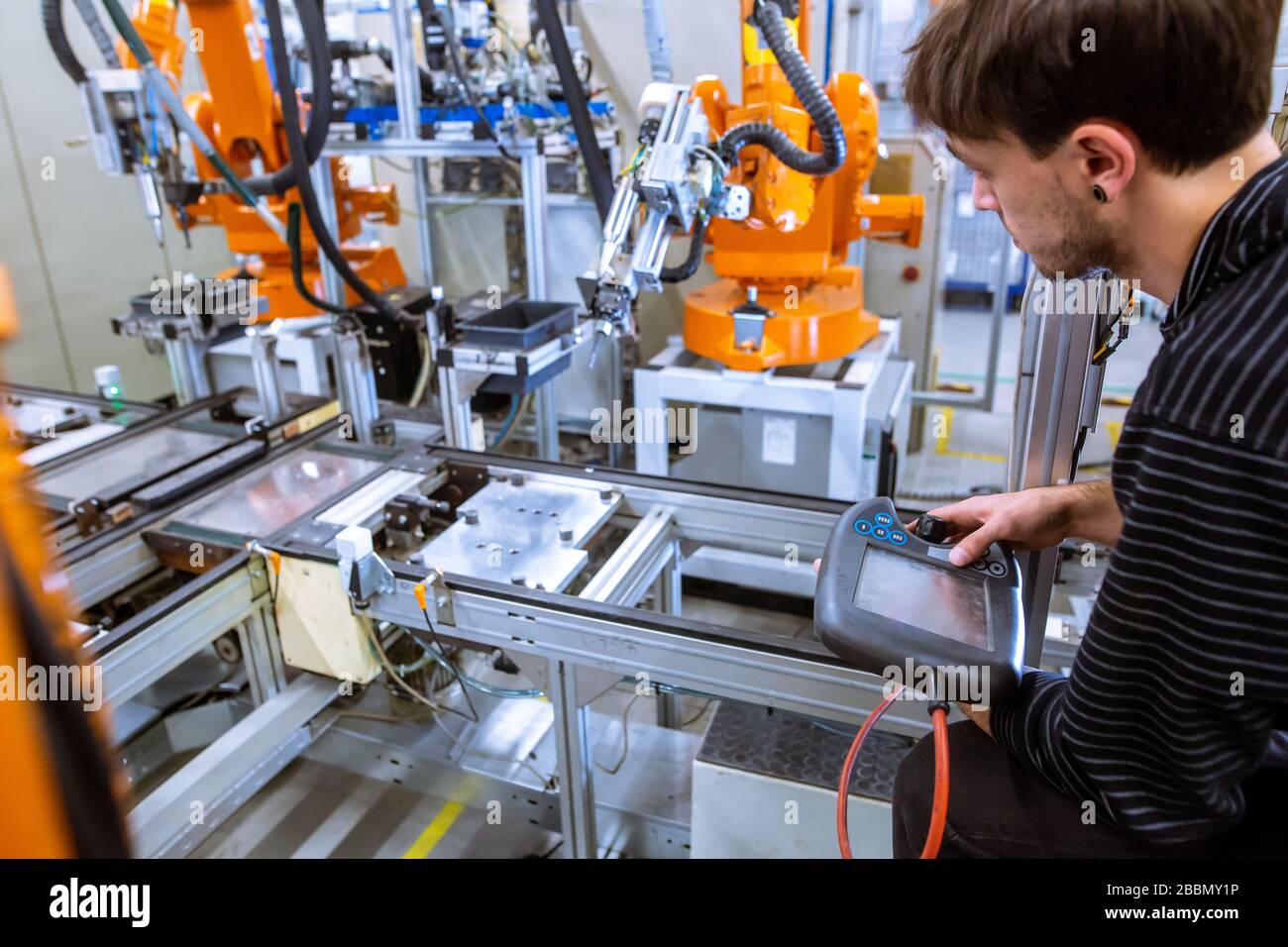 Engineer setting up automatic robot arms in smart factory, automotive industry, industrial concept Stock Photo
