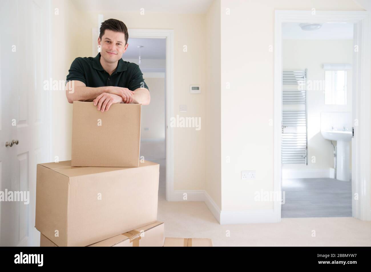 Portrait Of Removal Man Carrying Boxes Into New Home On Moving Day Stock Photo