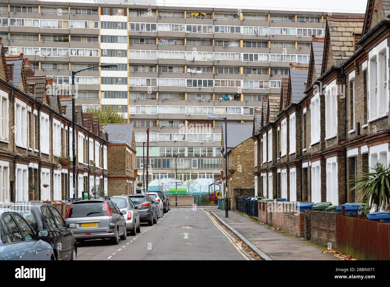 Traditional English terraced houses with huge council block Taplow House, Aylesbury Estate in the background in south east London Stock Photo