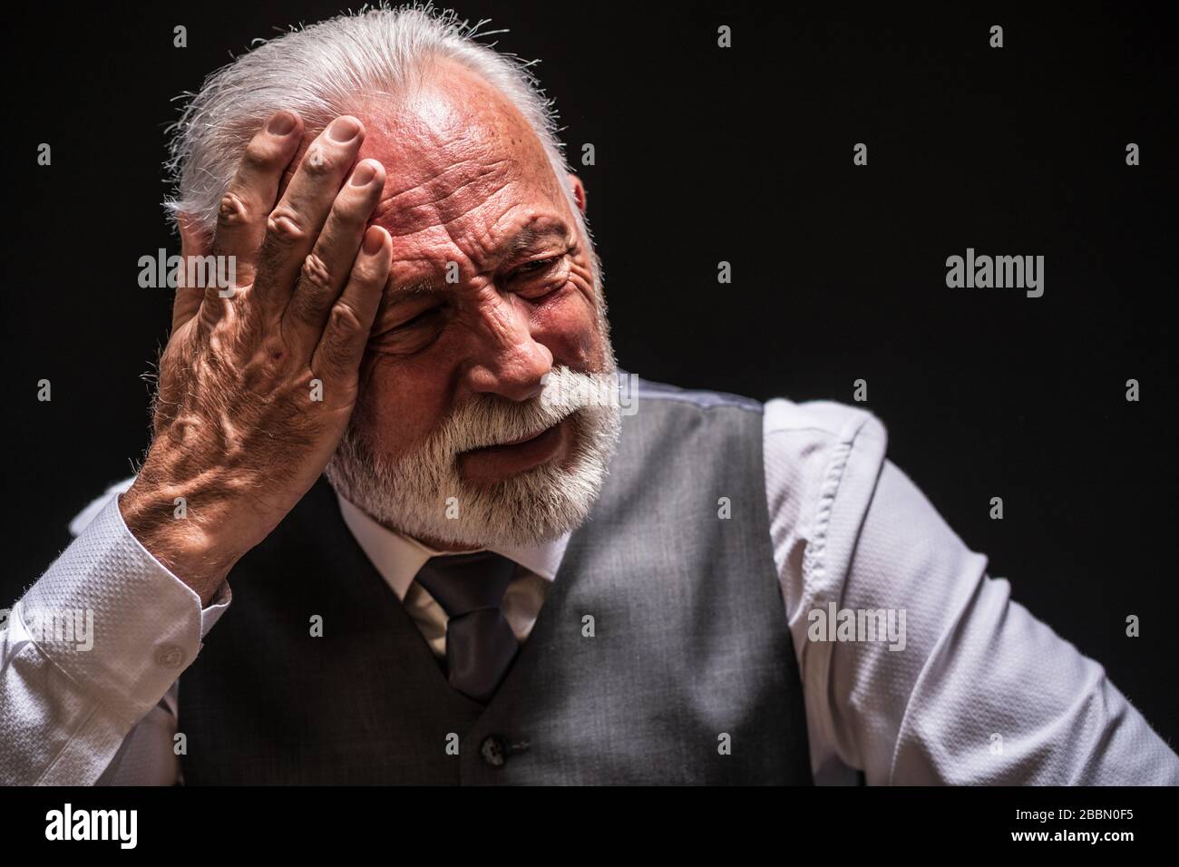 Portrait of depressed senior man on black background. Stock Photo