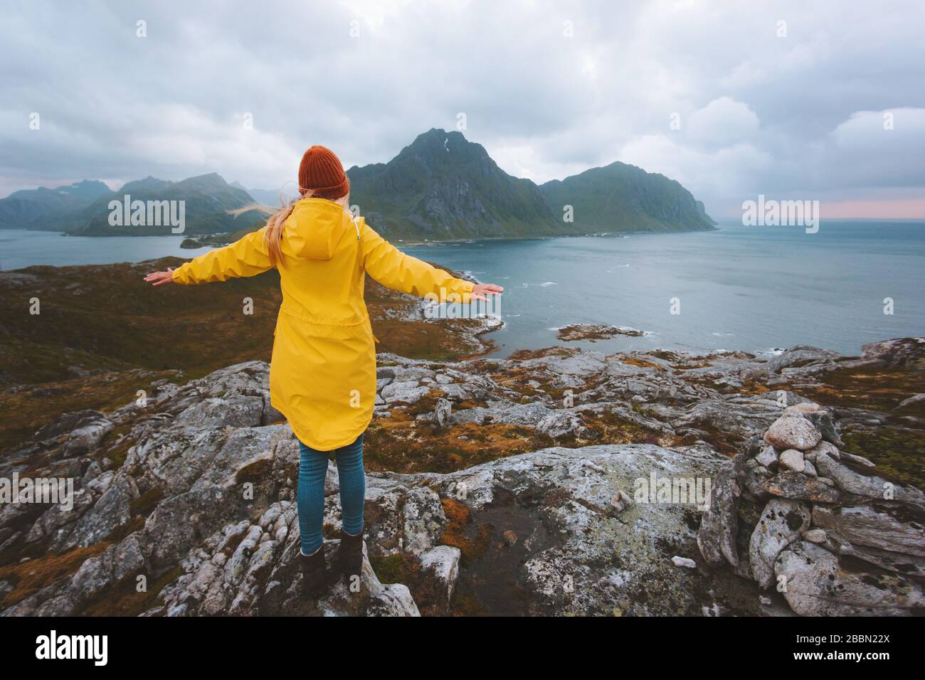Woman traveler raised hands enjoying rainy mountains view traveling in Norway alone active vacations healthy lifestyle outdoor Lofoten islands landsca Stock Photo