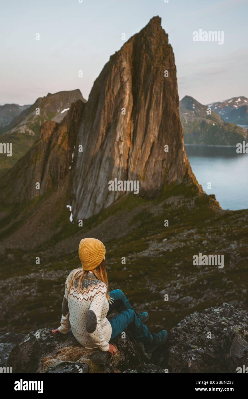 Woman traveler looking at Segla mountain sunset view hipster girl traveling alone in Norway adventure vacations healthy lifestyle outdoor evening land Stock Photo