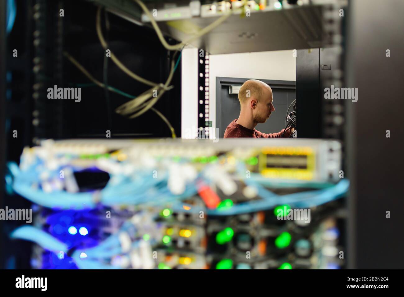 Man data center technician performing server maintenance. Replacing cables, Stock Photo