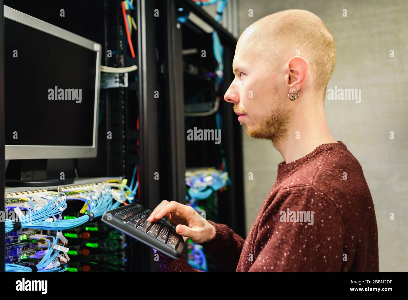 Man data center technician performing server maintenance. Using keyboard to configure infrastructure Stock Photo