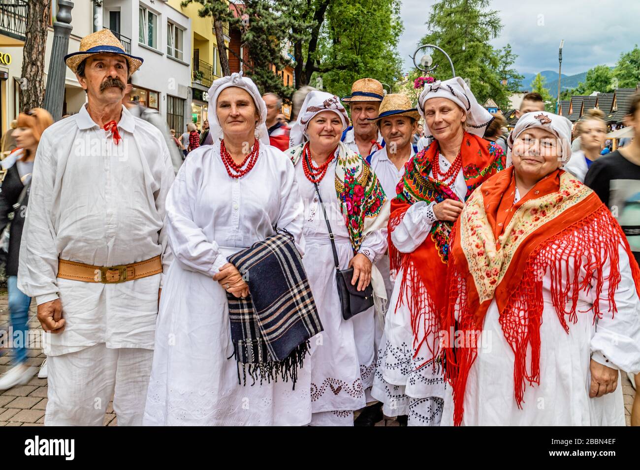 A group of people wearing a version of traditional costume in Zakopane town centre, Zakopane, southern Poland. July 2017. Stock Photo