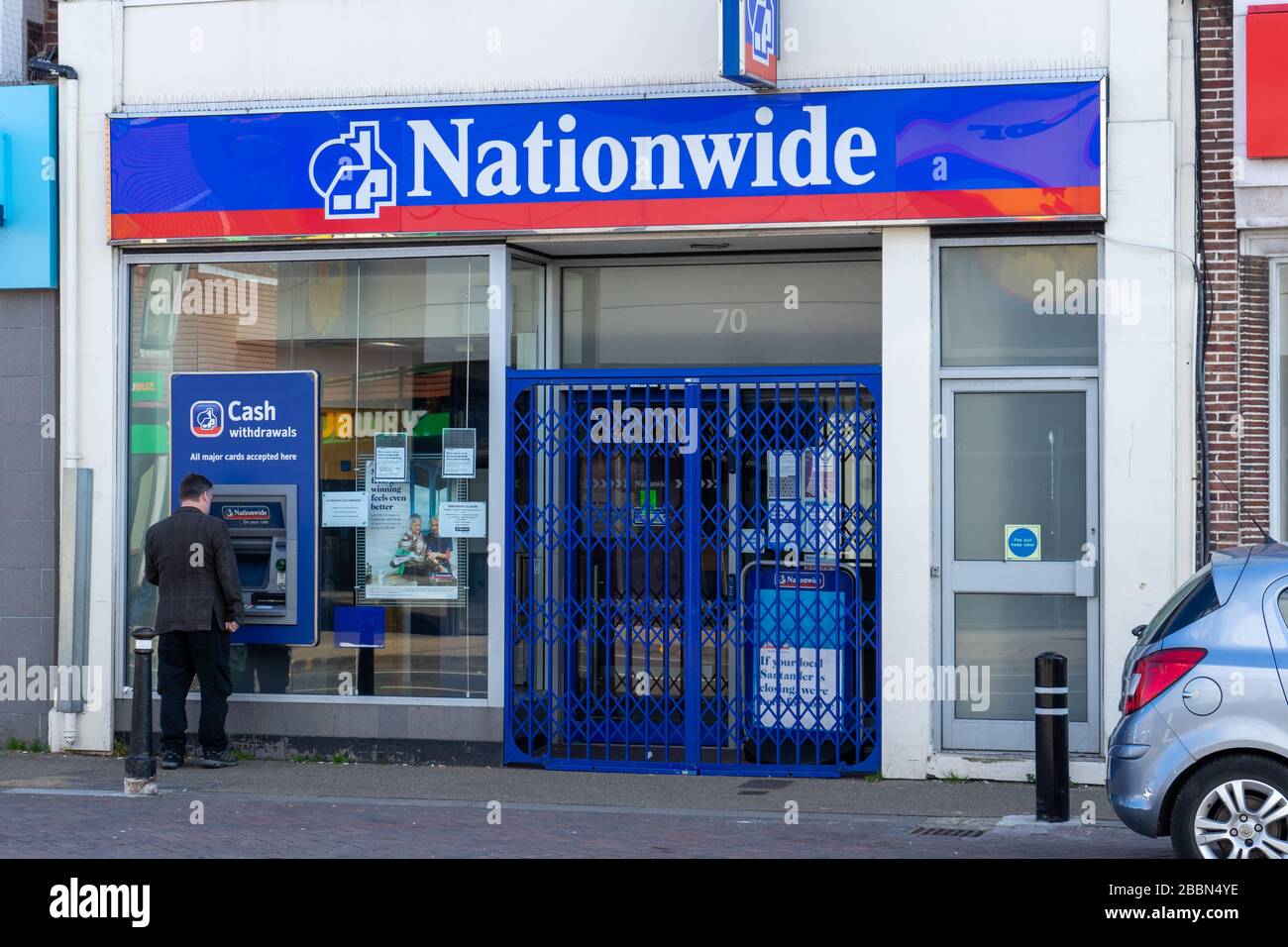 A man using a cashpoint or ATM outside a closed Nationwide Building society branch Stock Photo