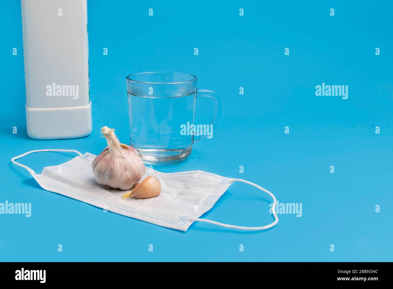 Coronavirus prevention myths concept. Drinking water, eating garlic, gargling bleach, face mask. Image with copy space, blue background Stock Photo