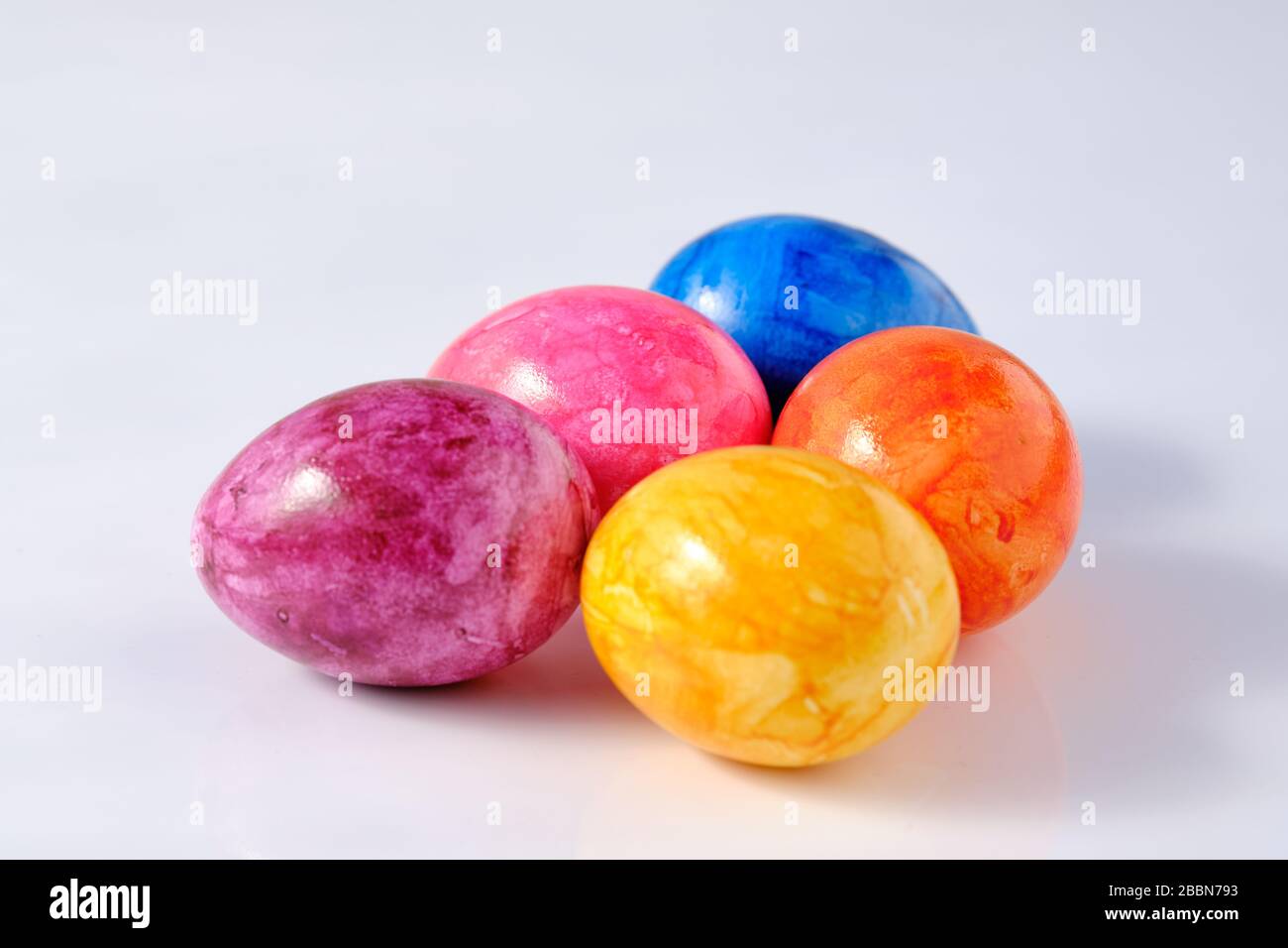Five naturally looking coloured Easter eggs lying isolated on white background with copy space. Stock Photo