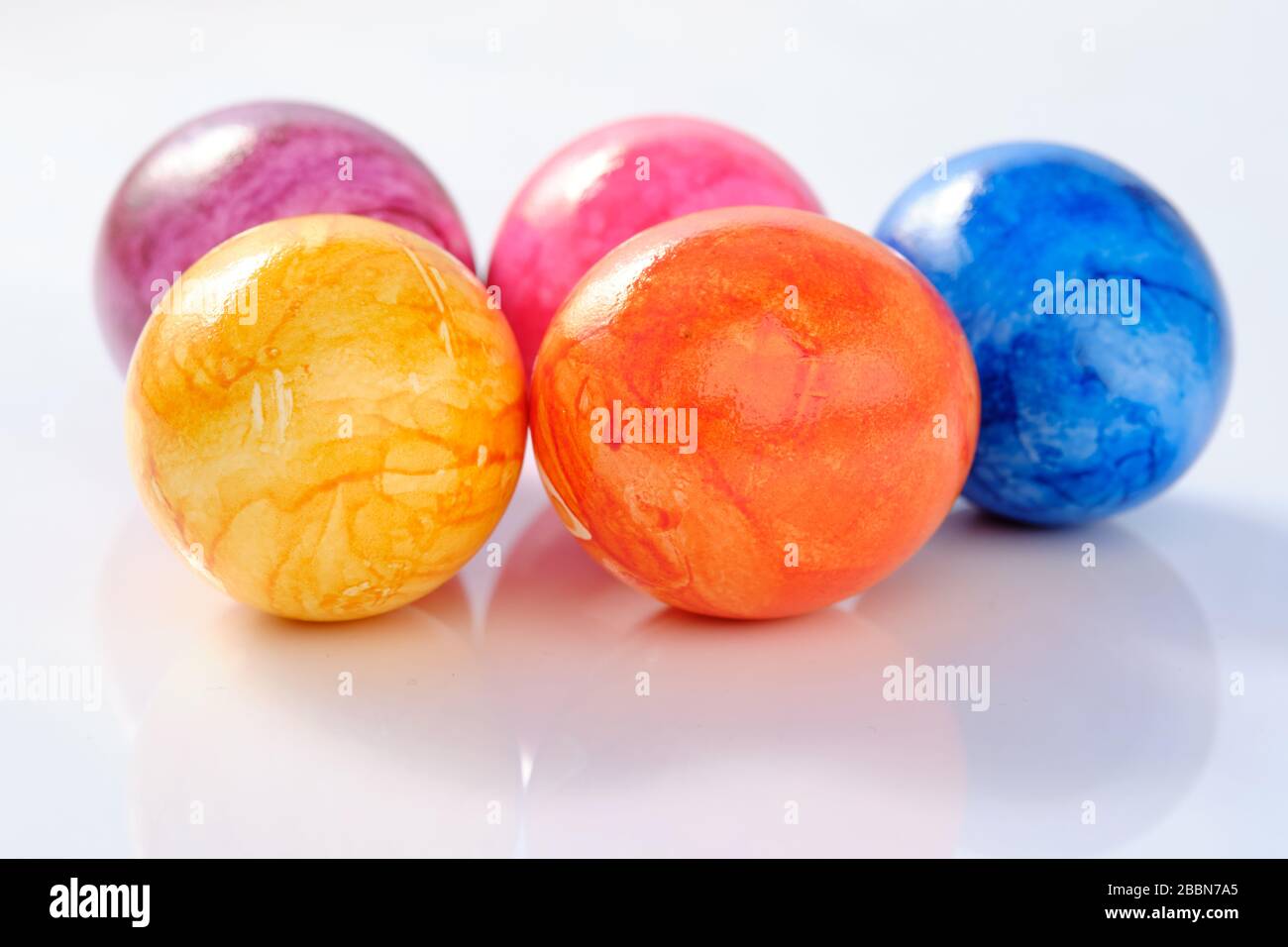 Five naturally looking coloured Easter eggs lying isolated on white background with copy space. Stock Photo