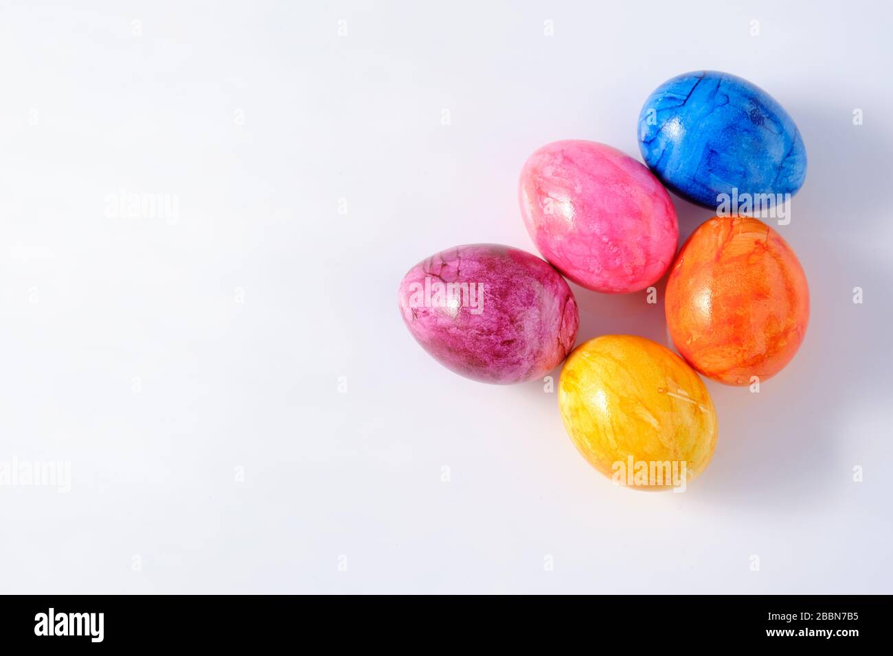 Five naturally looking coloured Easter eggs lying isolated on white ...