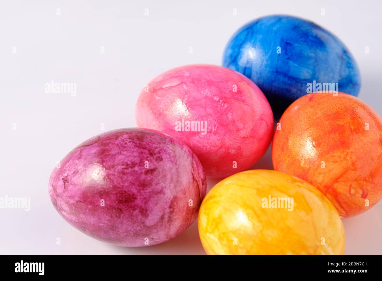 Five naturally looking coloured Easter eggs lying isolated on white background with copy space. Stock Photo