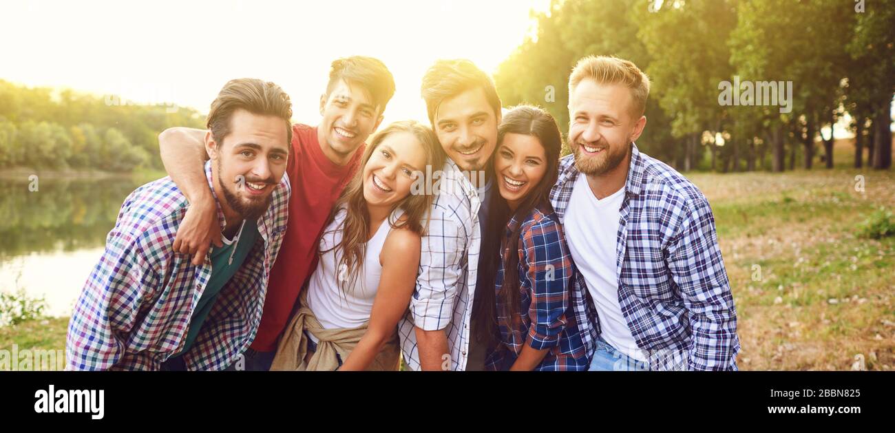 Group of friends cuddling while standing at a nature party. Young people have fun on a picnic. Stock Photo